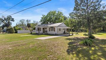 A single-story house with a front porch, a small yard, and a tree in front.