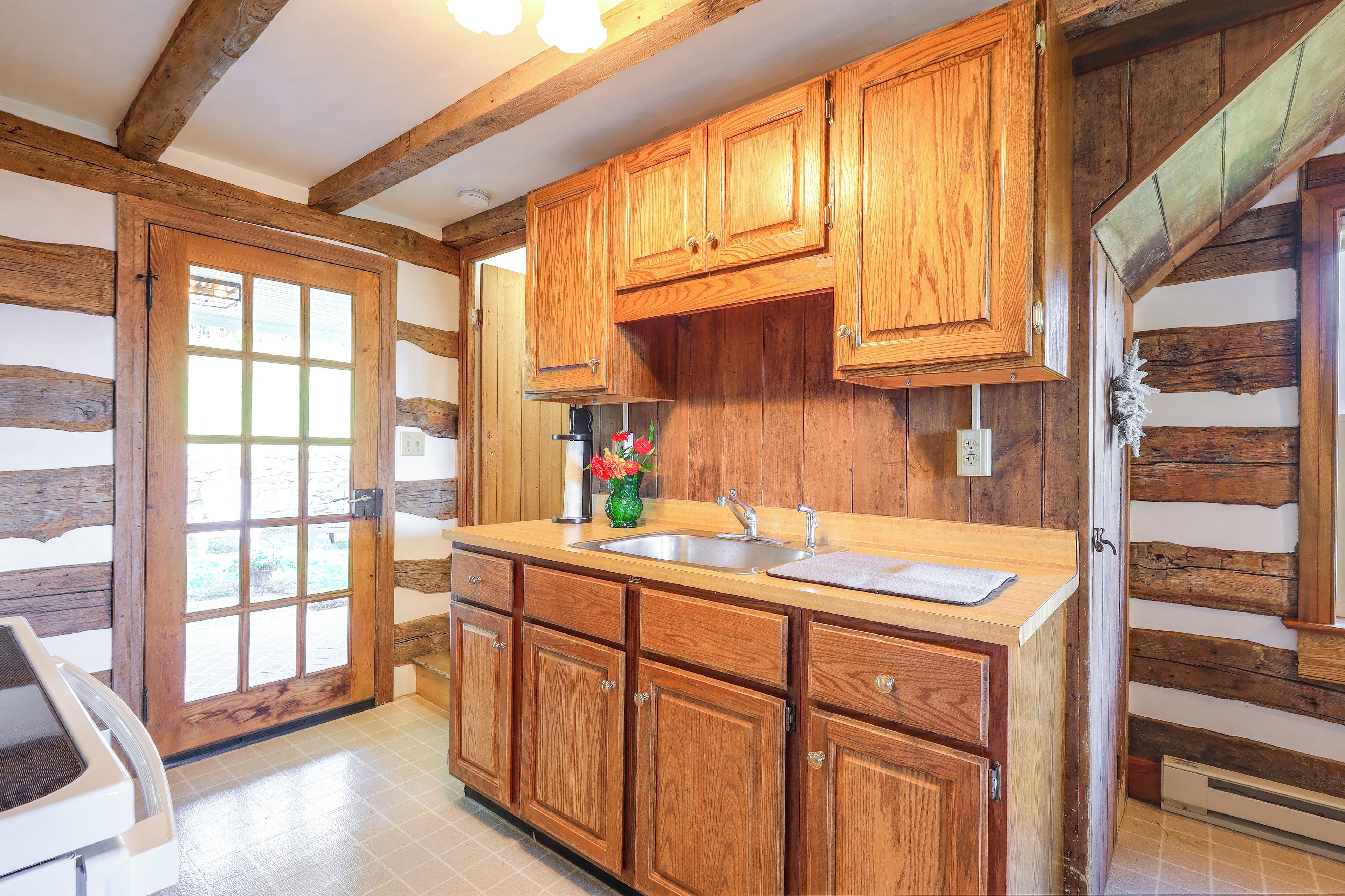 Una cocina con armarios de madera, un lavamanos y un ventanal.