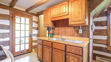 Una cocina con armarios de madera, un lavamanos y un ventanal.