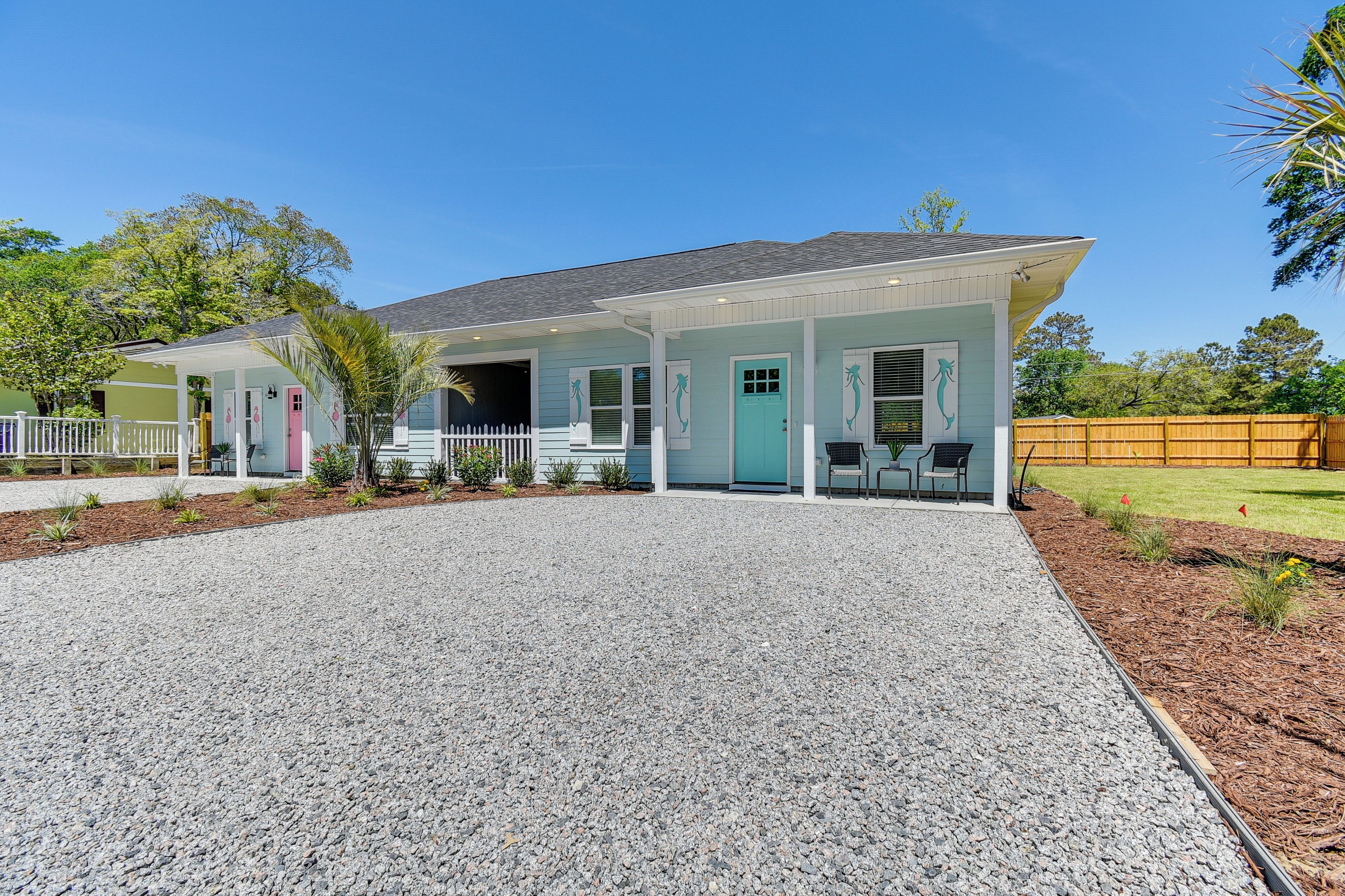 A two-story house with a covered porch, a gravel driveway, and a fenced yard.