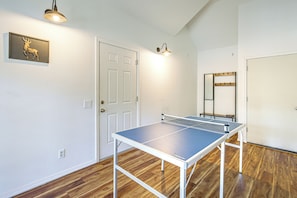A room with a ping pong table, a door, and a wall-mounted mirror.