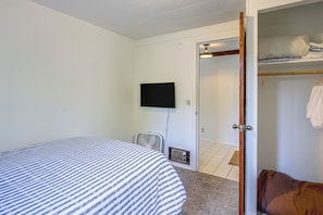A room with a bed, a television mounted on the wall, and a door leading to a closet with a hanging rack.
