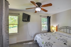 A bedroom with a bed, a ceiling fan, a TV mounted on the wall, and two windows with curtains. - Lakefront Escape in Vandalia: Ski, Fish & Stargaze (Vandalia)