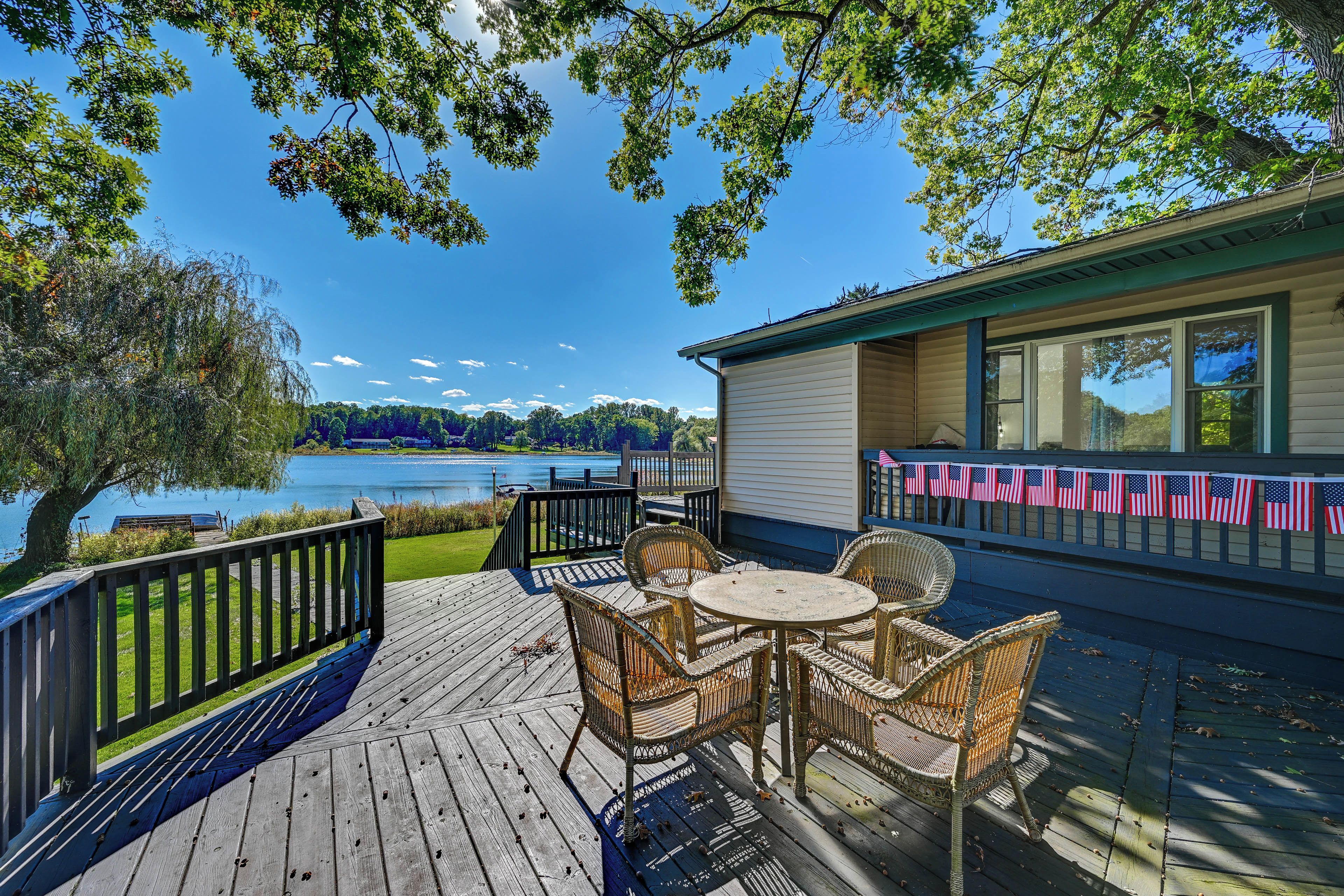 A wooden deck with wicker furniture overlooking a lake.