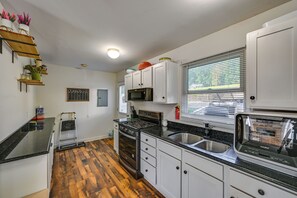 A compact kitchen with white cabinets, a black countertop, and a wooden floor. - Lakefront Escape in Vandalia: Ski, Fish & Stargaze (Vandalia)