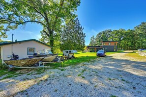 A gravel driveway leading to a house with a boat on a trailer, a small cabin, and a blue car parked nearby. - Lakefront Escape in Vandalia: Ski, Fish & Stargaze (Vandalia)