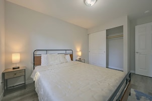 Un dormitorio con cama, lámparas de noche, armario y una puerta.