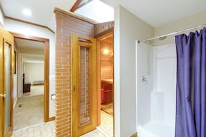 A bathroom with a shower, a wooden door, and a visible hallway leading to another room. - Walk to the Stadium & Clemson: 3BR w/ Parking! (Clemson)