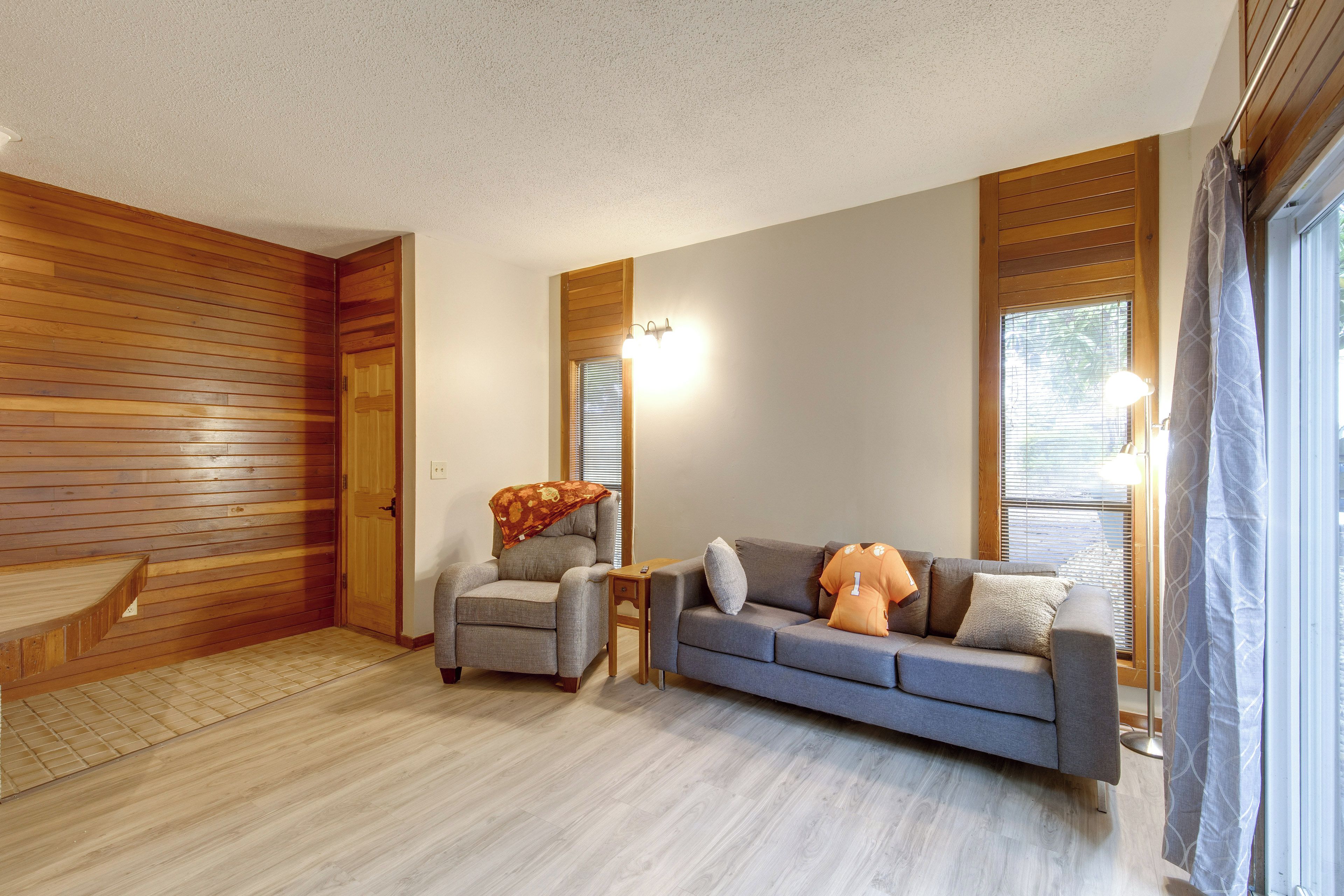 A room with a wooden floor, a grey sofa, a small table, and a wooden door.