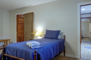 Un dormitorio con cama, mesita de noche, lámpara y puerta de madera.