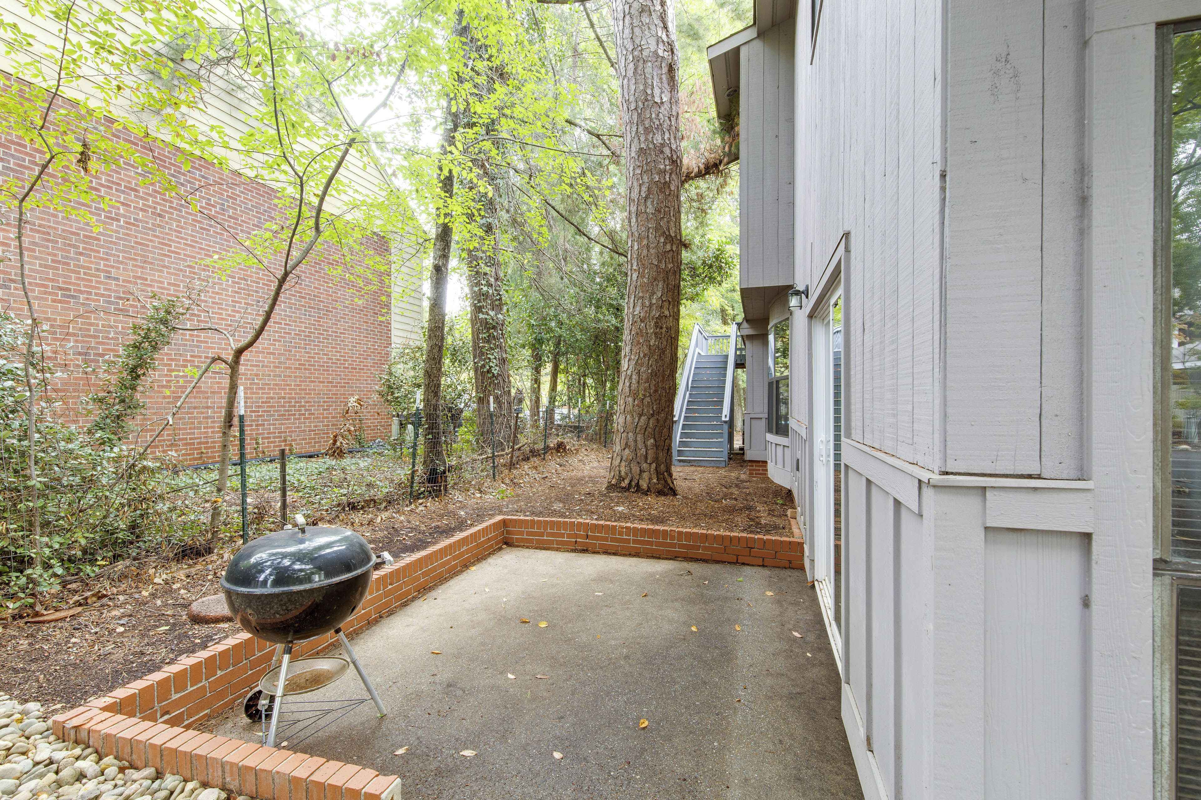 A backyard with a barbecue grill, a brick planter, and a white building.