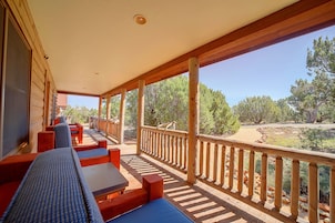 A covered outdoor seating area with wooden furniture and a view of a natural landscape.