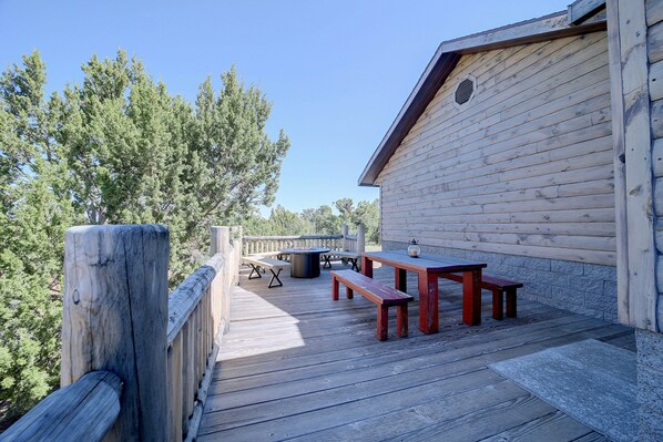 A wooden deck with picnic tables and benches, surrounded by trees. - On-site Hiking! Spacious Happy Jack Home w/ Deck (Happy Jack)