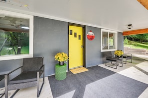A reception area with a yellow door, two wicker chairs, a green decorative planter with yellow flowers, and a welcome sign. - Lakefront Angler's Retreat w/ Dock Access (New Haven)