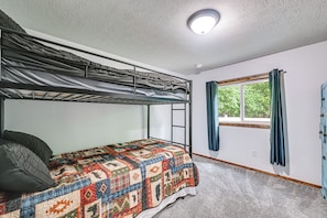 A bunk bed with a colorful quilt, a window with curtains, and a ceiling light. - Lakefront Angler's Retreat w/ Dock Access (New Haven)