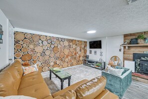 A living room with a wall of stacked logs, a leather sofa, a small table, and a bookshelf. - Lakefront Angler's Retreat w/ Dock Access (New Haven)