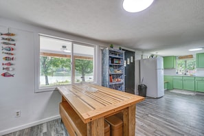 A kitchen with a wooden table, green cabinets, and a view of a lake through large windows. - Lakefront Angler's Retreat w/ Dock Access (New Haven)