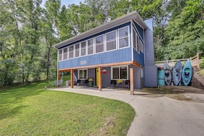 A two-story building with a covered patio area, a welcome sign, and kayaks stored against the wall. - Lakefront Angler's Retreat w/ Dock Access (New Haven)