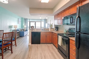 A modern kitchen with wooden cabinets, a black refrigerator, and a built-in oven. - Ocean-view Dunes Village Condo: Water Park & Pools (Myrtle Beach)