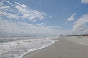 A beach with waves, a clear sky, and distant buildings. - Ocean-view Dunes Village Condo: Water Park & Pools (Myrtle Beach)
