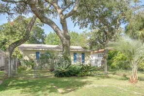 A two-story house with a fenced yard, surrounded by trees and vegetation. - Beach Escape 1 Mi to Okaloosa Island & Dtwn (Fort Walton Beach)
