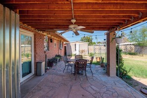 A covered patio with a ceiling fan, a table with chairs, and potted plants. - Studio 3 Mi to Tucson Airport! Bring Your Pups (Tucson)