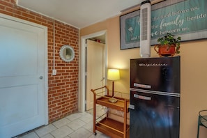 A kitchen with a refrigerator, a wooden cart, and a wall with a decorative sign. - Studio 3 Mi to Tucson Airport! Bring Your Pups (Tucson)