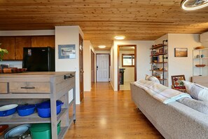 A modern kitchen with wooden cabinets, a black refrigerator, and a dining area with a sofa and a coffee table. - Waterfront Bellingham Home w/ Fire Pits & Patio (Bellingham)