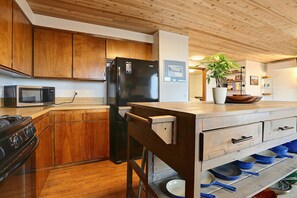 A kitchen with wooden cabinets, a black refrigerator, a microwave, and a stove. - Waterfront Bellingham Home w/ Fire Pits & Patio (Bellingham)