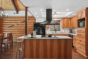 Una cocina moderna con armarios de madera, una isla central y una campana extractora negra.