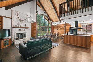 Amplia sala de estar con chimenea, un sofá grande y un comedor con muebles de madera.