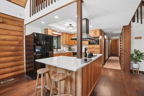 A modern kitchen with a central island, wooden cabinets, and a stainless steel refrigerator. - Cabin & Guest House Near Sandy River Trails! (Brightwood)