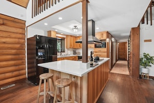 Una cocina moderna con una isla central, armarios de madera y un refrigerador de acero inoxidable.