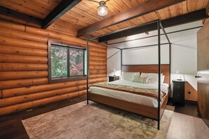 A log cabin bedroom with a four-poster bed, a window with blinds, a bedside table, and a nightstand. - Cabin & Guest House Near Sandy River Trails! (Brightwood)