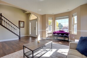 A spacious living room with hardwood flooring, a coffee table, a sofa, and a staircase with a wooden railing. - Extended Mtn-view Stay w/ Hot Tub Near Skiing (Mountain Green)