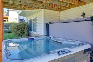 Ein Whirlpool mit Bedienfeld, eine Holzterrasse und ein Haus im Hintergrund.