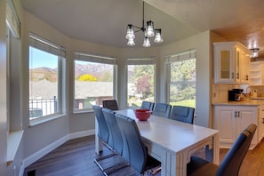A kitchen with a dining table, chairs, and a view of mountains. - Extended Mtn-view Stay w/ Hot Tub Near Skiing (Mountain Green)