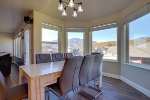 A dining area with a table and chairs, large windows with mountain views, and a ceiling light fixture. - Extended Mtn-view Stay w/ Hot Tub Near Skiing (Mountain Green)