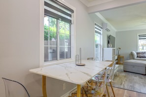 Een moderne keuken met een marmeren aanrecht, een eettafel met stoelen en uitzicht op het landschap door grote ramen.