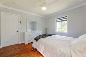 Ein Schlafzimmer mit Bett, Schminktisch, Spiegel, Deckenventilator und Fenster.
