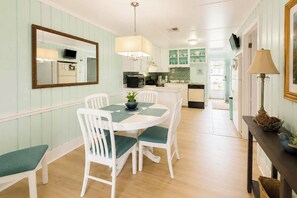 A dining area with a white table and chairs, a mirror on the wall, and a kitchen in the background. - 'paradise Found' on Lake Louisa: Swim + Fish! (Clermont)
