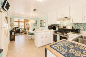 A kitchen with white cabinets, a stove, a microwave, and a sink. There is a dining area with a table and chairs. - 'paradise Found' on Lake Louisa: Swim + Fish! (Clermont)