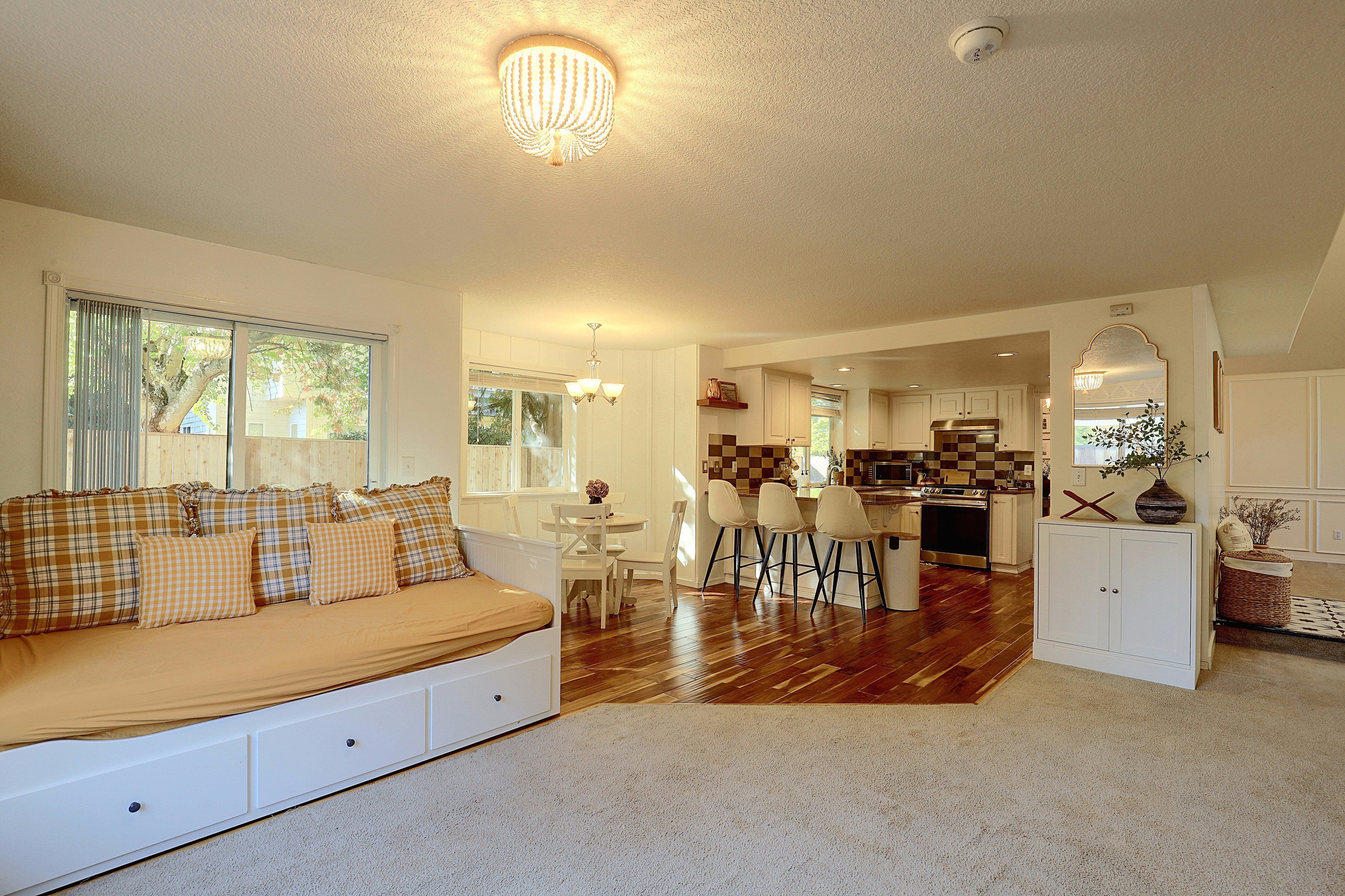 A spacious living area with a sofa, a dining table, and a kitchen in the background.
