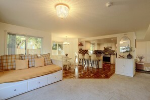 A spacious living area with a sofa, a dining table, and a kitchen in the background. - Spacious Hillsboro Home w/ Fenced Yard (Hillsboro)