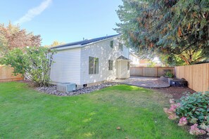 A single-story house with a small porch, a fenced backyard, and a front yard with grass and a tree. - Spacious Hillsboro Home w/ Fenced Yard (Hillsboro)
