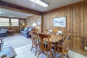 A room with a wooden paneled wall, a dining table with chairs, a sofa, a lamp, and a framed picture on the wall. - 'lake Life' Retreat in Clermont w/ Pool & Pier (Clermont)