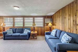 A room with two blue sofas, a wooden wall, and a ceiling fan. - 'lake Life' Retreat in Clermont w/ Pool & Pier (Clermont)