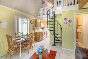 A dining area with a wooden table and chairs, a kitchen with wooden cabinets, and a staircase leading to an upper level. - 'livin' on Sunshine' Lake Louisa Escape! (Clermont)