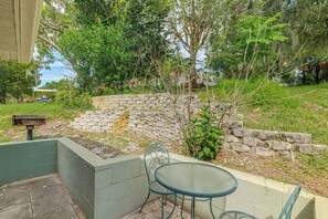 A patio area with a stone wall, a small table, and chairs. - 'livin' on Sunshine' Lake Louisa Escape! (Clermont)