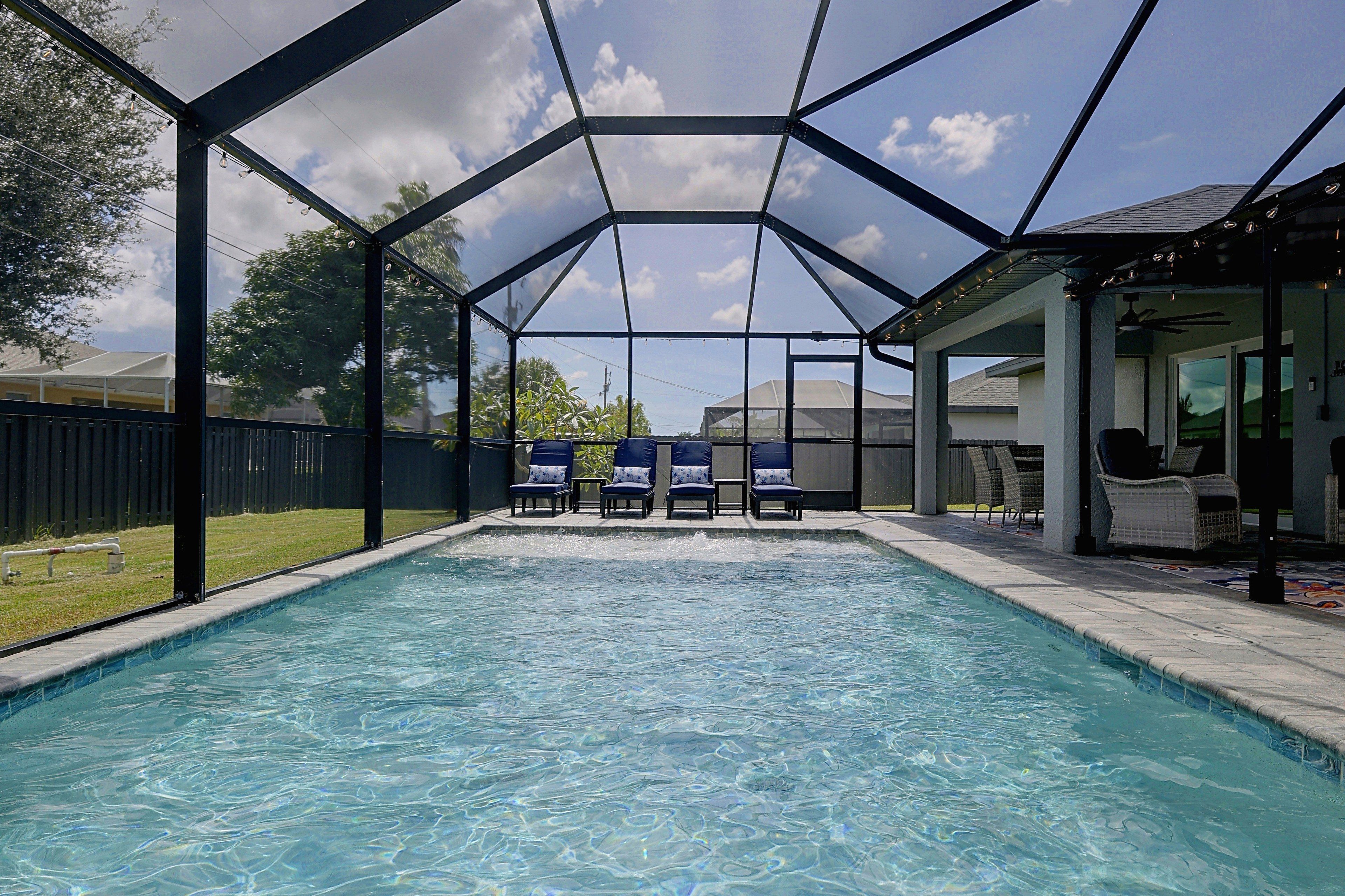 Una piscina con zona cubierta, sillas de descanso y un patio con mobiliario exterior.